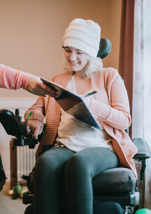 young girl in powered wheelchair with clipboard