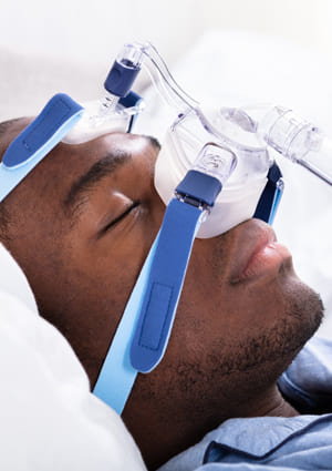 man in bed sleeping with CPAP mask