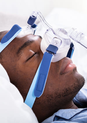 man in bed sleeping with CPAP mask