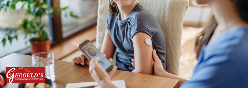 Mom checking child's blood sugar on her phone with hand on child's arm that has CGM sensor