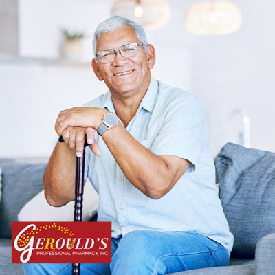 Senior man smiling while sitting on a couch with his hands on top of a cane handle