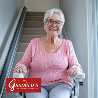 Senior woman on a stair lift at the bottom of the stairs in her home
